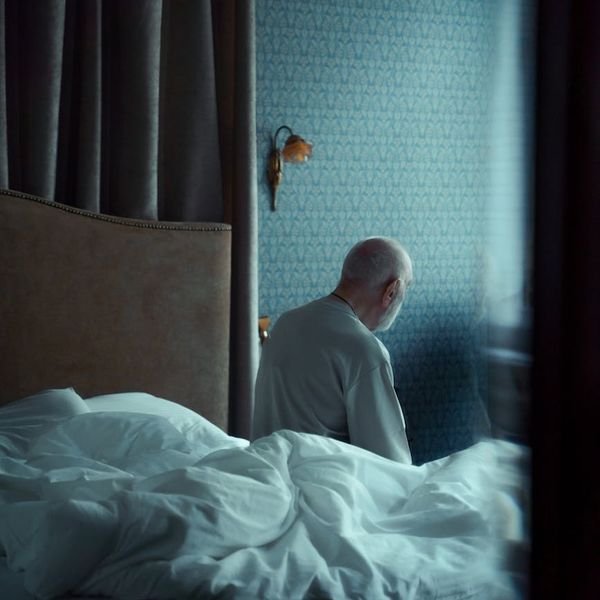 Person sitting in a comfortable, meditative pose in a brightly lit, minimalist room.