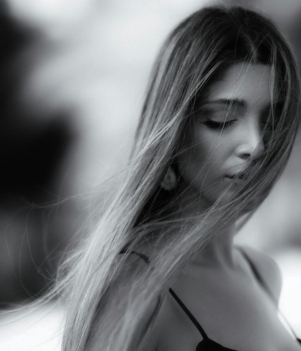 Woman with a serene expression, gently closing her eyes in a calm environment.